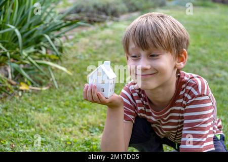 ragazzo che gli tiene un modello di casa in mano Foto Stock