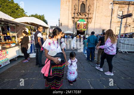 Morelia, Messico, 10 dicembre 2022, Una madre guarda indietro ad un penitente durante il giorno della celebrazione della Vergine di Guadalupe al Tempio di Guadalupe. Milioni di messicani di tutte le età celebrano questa festa religiosa che culmina il 12th dicembre vestendo come Juan Diego o la Vergine di Guadalupe e andando al tempio dedicato alla vergine in ogni città. Brian Overcast/Alamy Live News. Foto Stock