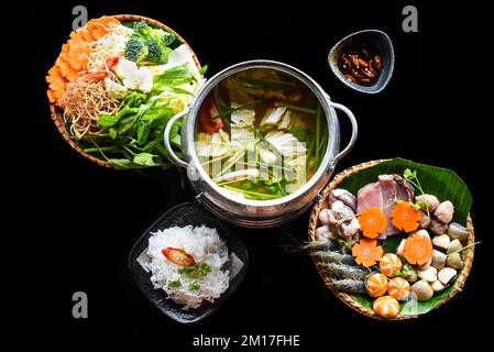 Hot pot coreano con cibo di mare e tagliatelle su sfondo nero Foto Stock