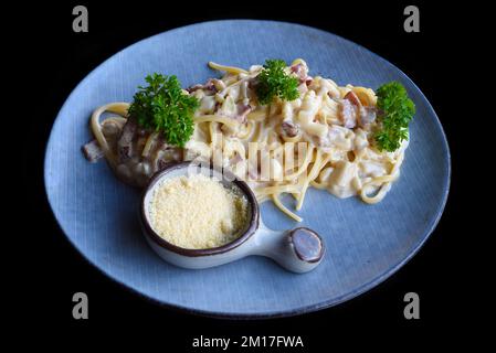 Pasta carbonara con pancetta su piatto blu isolato su sfondo nero vista dall'alto Foto Stock