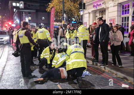 Broad Street, Birmingham, dicembre 10th 2022 - questo è stato il momento drammatico in cui due uomini, che inizialmente sono stati cacciati dal nightclub Reflex, sono stati affrontati a terra da ufficiali dopo che si sono tirati indietro verso i festaioli in coda per entrare. Qualcuno all'interno della mischia si sentiva dire "mi sta mordendo" gli ufficiali della polizia delle West Midlands discesero rapidamente sull'incidente di Broad Street sabato 10 dicembre sera. Uno dei volti dei trasgressori è stato sanguinato ed entrambi sono stati portati a mano in furgoni di polizia in attesa. La notte aveva iniziato la calma a causa della sconfitta del 2-1 contro la Francia. Alcuni partygoers sono stati visti st Foto Stock