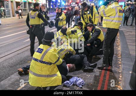 Broad Street, Birmingham, dicembre 10th 2022 - questo è stato il momento drammatico in cui due uomini, che inizialmente sono stati cacciati dal nightclub Reflex, sono stati affrontati a terra da ufficiali dopo che si sono tirati indietro verso i festaioli in coda per entrare. Qualcuno all'interno della mischia si sentiva dire "mi sta mordendo" gli ufficiali della polizia delle West Midlands discesero rapidamente sull'incidente di Broad Street sabato 10 dicembre sera. Uno dei volti dei trasgressori è stato sanguinato ed entrambi sono stati portati a mano in furgoni di polizia in attesa. La notte aveva iniziato la calma a causa della sconfitta del 2-1 contro la Francia. Alcuni partygoers sono stati visti st Foto Stock