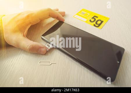 Scheda SIM etichettata 5g. Sostituzione di una scheda SIM in un telefono cellulare con Internet ad alta velocità. Foto Stock