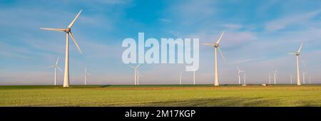 Vista al parco dei mulini a vento con turbine eoliche durante l'inverno che generano elettricità con un concetto di energia verde cielo blu Foto Stock