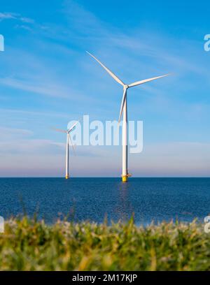 Vista al parco dei mulini a vento con turbine eoliche durante l'inverno che generano elettricità con un concetto di energia verde cielo blu Foto Stock