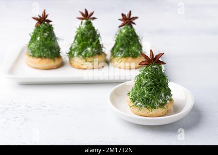 Spuntino di Natale sotto forma di alberi. Deliziose tartine di formaggio cremoso con noci, aglio e aneto tritato su biscotti fatti in casa, decorati con un ani Foto Stock