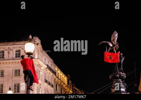 Londra, Regno Unito. 10th Dec, 2022. Un sostenitore del calcio marocchino ha visto appendere una bandiera marocchina su un palco a Piccadilly Circus per celebrare la vittoria sul Portogallo nella Coppa del mondo FIFA 2022. Il Marocco, gli altri paesi del Nord Africa e del Medio Oriente residenti a Londra, festeggiano nella città di Londra dopo che il Marocco batte il Portogallo nel quarto di finale della Coppa del mondo FIFA 2022. Il Marocco è il primo paese africano che si è trasformato in semifinale nella Coppa del mondo nella storia. (Foto di Hesther ng/SOPA Images/Sipa USA) Credit: Sipa USA/Alamy Live News Foto Stock