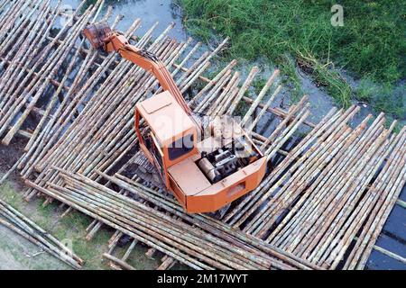 Il vecchio escavatore sul ponteggio in legno sulla piscina in preparazione al lavoro. Foto Stock
