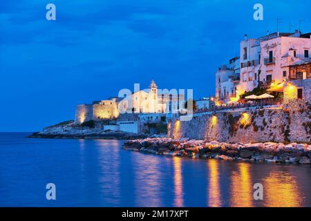 Punta San Francesco con chiesa illuminata di San Francesco e centro storico all'ora blu, Vieste, Gargano, Foggia, Puglia, Puglia, Italia Meridionale, Italia Foto Stock