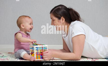 La madre gioca i giocattoli con la ragazza eccitata del bambino e gode il fine settimana Foto Stock