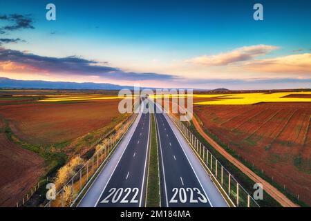 Veduta aerea dell'autostrada al tramonto di 2022 anno e di nuovo anno 2023. Trasporti, logistica e agricoltura Foto Stock