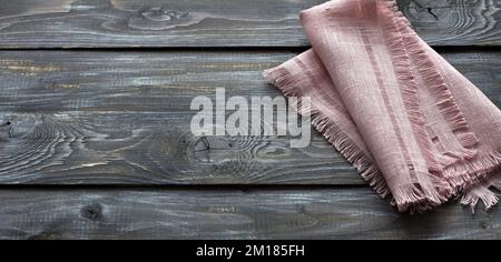 Tovagliolo di lino rosa con frangia su sfondo di legno, stile rustico, vista dall'alto, spazio Foto Stock
