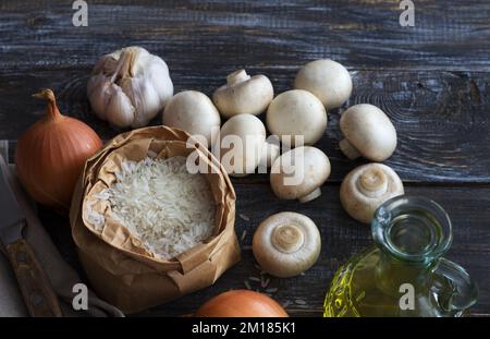 Ingredienti per deliziosi piatti vegani. Riso basmati bianco, aglio e champignons su tavolo di legno, vista dall'alto, spazio, orizzontale Foto Stock