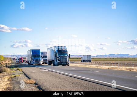Convoglio di un trasporto professionale commerciale di grado industriale di diversi semirimorchi con semirimorchi che guidano sul rettilineo highwa Foto Stock