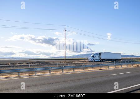 Semirimorchio bianco per impieghi industriali con cabina alta per il trasporto di carichi commerciali congelati in semirimorchio frigorifero in marcia sul tetto Foto Stock