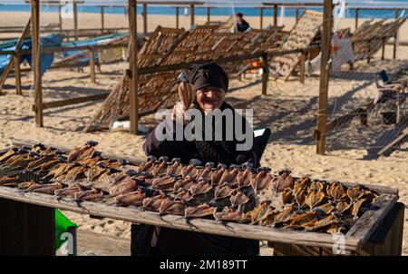 Nazare, Portogallo - 09.12.2022: Vecchia signora in nero vende pesce secco Foto Stock