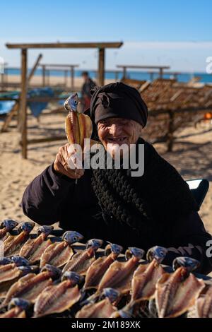 Nazare, Portogallo - 09.12.2022: Vecchia signora in nero vende pesce secco Foto Stock