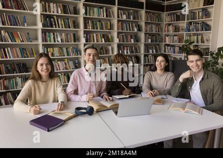 Allegri studenti adolescenti multietnici che studiano insieme in biblioteca universitaria Foto Stock