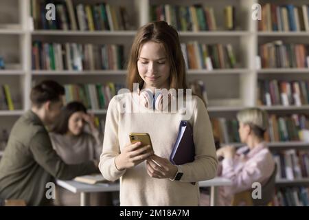 Concentrato piuttosto giovane studente di scuola superiore a scrivere sullo smartphone Foto Stock