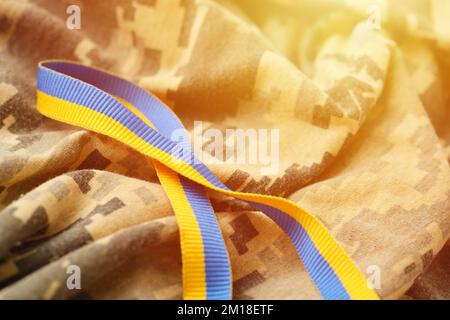 Tessuto camouflage militare digitale Pixeled con nastro nei colori blu e giallo. Attributi di uniforme soldato patriottico ucraino Foto Stock