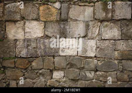 Struttura di un muro di pietra con molte grandi pietre marroni e grigie armati di cemento. Vecchio castello di pietra sfondo struttura muraria per uso medievale. Parte di un edificio in pietra come sfondo Foto Stock