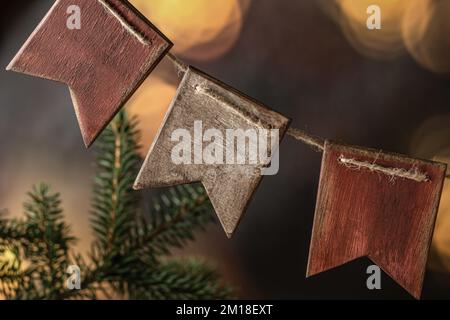 Ghirlanda di bandiere in legno per abeti fatte a mano. Accogliente carta da parati invernale di natale di Capodanno con luci bokeh. Orientamento orizzontale Foto Stock