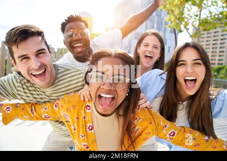 Amici giovani felici guardando Camera e ridendo sorridente Gruppo di persone che si divertono insieme all'aria aperta Foto Stock