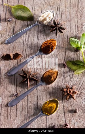 Spezie tipiche brasiliane - mandorle, cannella, paprika e curcuma in polvere in un cucchiaio su un tavolo di legno rustico. Foto Stock