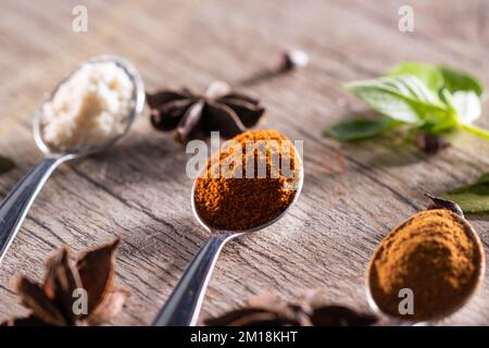 Spezie tipiche brasiliane - mandorle, cannella, paprika e curcuma in polvere in un cucchiaio su un tavolo di legno rustico. Foto Stock