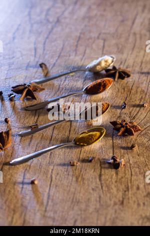 Spezie tipiche brasiliane - mandorle, cannella, paprika e curcuma in polvere in un cucchiaio su un tavolo di legno rustico. Foto Stock