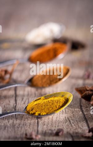 Spezie tipiche brasiliane - mandorle, cannella, paprika e curcuma in polvere in un cucchiaio su un tavolo di legno rustico. Foto Stock