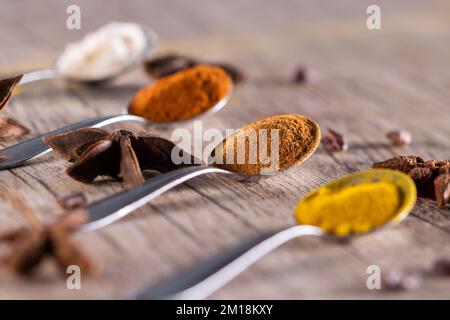 Spezie tipiche brasiliane - mandorle, cannella, paprika e curcuma in polvere in un cucchiaio su un tavolo di legno rustico. Foto Stock
