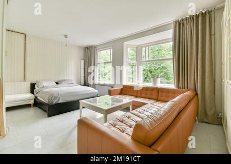 una camera da letto con un divano arancione e un letto bianco in camera è molto spaziosa, ma non è troppo Foto Stock