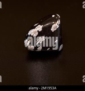 Macro immagine a colori di una lucida 'Snowflake Obsidian' una gemma di cristallo semi-preziosa usata nella terapia di guarigione dei cristalli Foto Stock