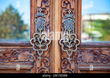 Vista ravvicinata della porta con splendide maniglie in metallo intagliate. Foto Stock