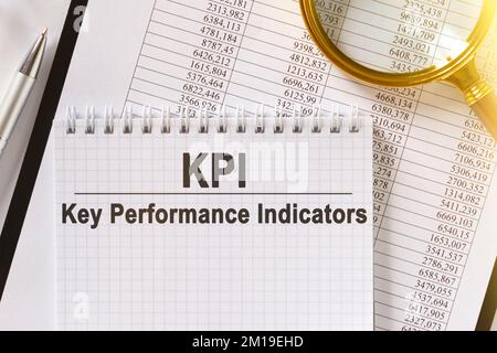Sulla tabella sono riportati i rapporti finanziari, una penna, una lente d'ingrandimento e un quaderno con l'iscrizione - KPI. Indicatori chiave delle prestazioni. Business e fina Foto Stock