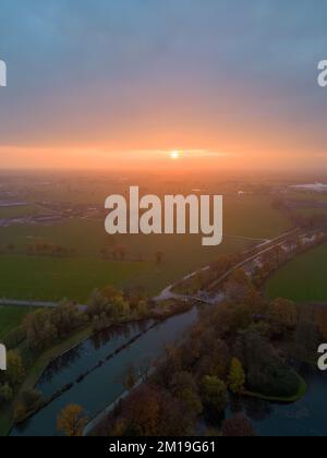 Vista aerea di infiniti pascoli lussureggianti e terreni agricoli del Belgio sotto un suggestivo cielo colorato al tramonto. Bella campagna di anversa con campi verde smeraldo e prati. Paesaggio rurale al tramonto. Foto di alta qualità Foto Stock