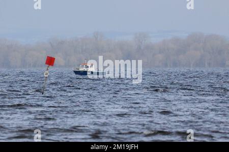 South Shore Lough Neagh, vicino a Lurgan, Contea di Armagh, Irlanda del Nord, Regno Unito. 11 Dec 2022. Tempo nel Regno Unito - l'incantesimo freddo continua con temperature che scenda a -7C in alcune parti dell'Irlanda del Nord durante la notte. Un po' di sole ha spinto la temperatura fino alle 4C:00 circa all'ora di pranzo, ma anche la leggera brezza è molto fredda. Una barca fuori sul lough in una doccia leggera. Credit: CAZIMB/Alamy Live News. Foto Stock