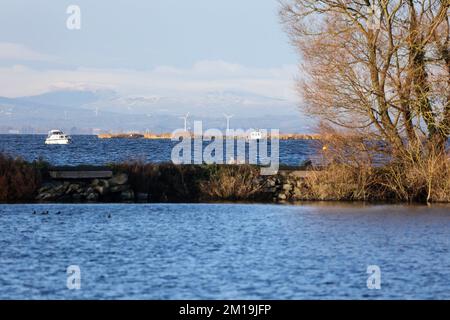 South Shore Lough Neagh, vicino a Lurgan, Contea di Armagh, Irlanda del Nord, Regno Unito. 11 Dec 2022. Tempo nel Regno Unito - l'incantesimo freddo continua con temperature che scenda a -7C in alcune parti dell'Irlanda del Nord durante la notte. Un po' di sole ha spinto la temperatura fino alle 4C:00 circa all'ora di pranzo, ma anche la leggera brezza è molto fredda. Due barche in barca a vela sul Lough Neagh in un soleggiato pomeriggio invernale con la neve sulle montagne Sperrin sullo sfondo. Credit: CAZIMB/Alamy Live News. Foto Stock