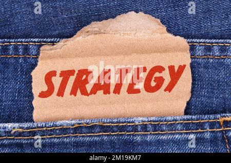 Affari e finanza. Una scatola di cartone con la strategia di iscrizione si stacca dai jeans. Foto Stock