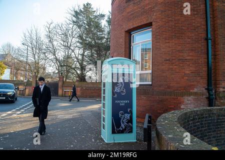 Eton, Windsor, Berkshire, Regno Unito. 8th dicembre 2022. Un ragazzo dell'Eton College passa davanti a un'ex cassetta telefonica all'esterno dell'Eton College che è stata dipinta di un verde chiaro e che ha avuto un'opera d'arte del Founder's Day. Ogni anno l'Eton College festeggia la Founder's Day verso il 4 giugno. I ragazzi dell'Eton College si vestono in abito a canottaggio e indossano dei boaters con fiori freschi su di loro e costellano il Tamigi. Credito: Maureen McLean/Alamy Foto Stock