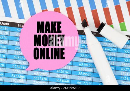 Concetto economico e commerciale. Sul bilancio e le tabelle ci è un contrassegno ed un adesivo con l'iscrizione - FACCIA I SOLDI IN LINEA Foto Stock