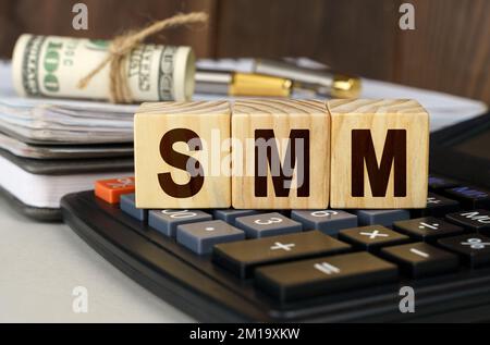 Finanza ed economia. Sul tavolo ci sono soldi, una calcolatrice, un notebook e cubi con l'iscrizione - SMM Foto Stock