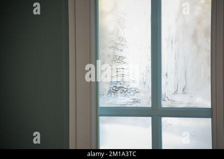 ghiaccio congelato su un vetro della finestra in una fredda giornata invernale. la luce del sole splende attraverso il vetro della stanza Foto Stock