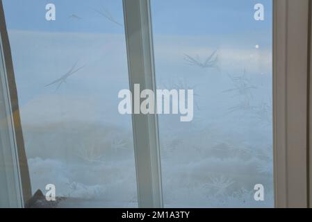 ghiaccio congelato su un vetro della finestra in una fredda giornata invernale. la luce del sole splende attraverso il vetro della stanza Foto Stock