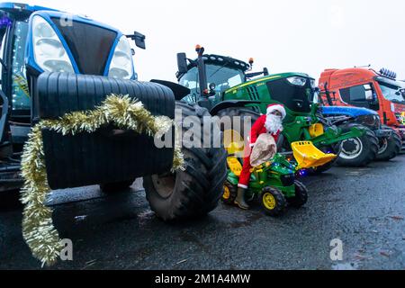 Bridgnorth, Shropshire, Regno Unito. 11th Dec, 2022. Un ragazzino vestito mentre Babbo Natale guida il suo trattore giocattolo tra i trattori reali di dimensioni reali che si sono riuniti per il Bridgnorth Festive Charity Tractor Run 2022. Oltre 100 trattori agricoli formarono una processione e guidarono attraverso i villaggi di Shropshire dal mercato del bestiame di Bridgnorth per raccogliere denaro per Hope House Children's Hospices. Credit: Peter Lopeman/Alamy Live News Foto Stock