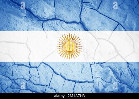 Bandiera dell'Argentina. Simbolo dell'Argentina. Bandiera sullo sfondo di terra secca spaccata. Argentina bandiera con concetto di siccità Foto Stock