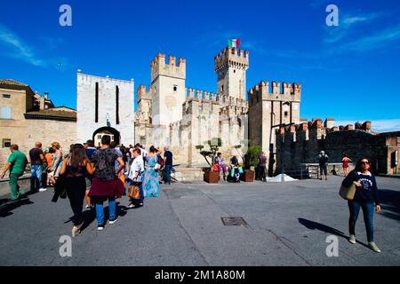 Persone nella piazza di fronte al castello d'acqua Scaligero nella città di Sirmione sul Lago di Garda in Italia. Foto Stock