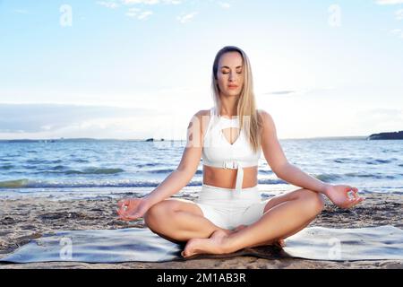 attraente donna che pratica yoga vicino al lago. Foto Stock
