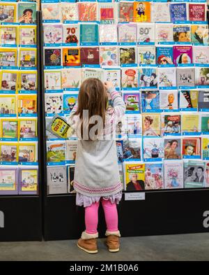 Piccola ragazza shopping felice. Una ragazza in una sezione di carte regalo nel negozio. Regali e regali. Foto di strada, fuoco selettivo-Surrey BC Canada-novembre Foto Stock